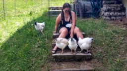 tamara sitting in the garden with four white chickens