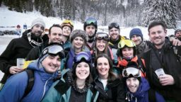 group of smiling people in ski gear with snowy trees and mountain in the distance